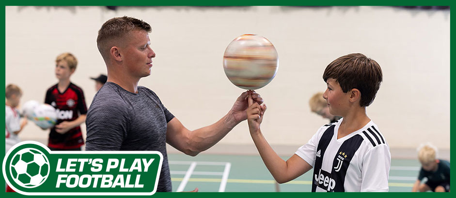 Jamie Knight Freestyle Football coach helping a child spin a football on his fingertip